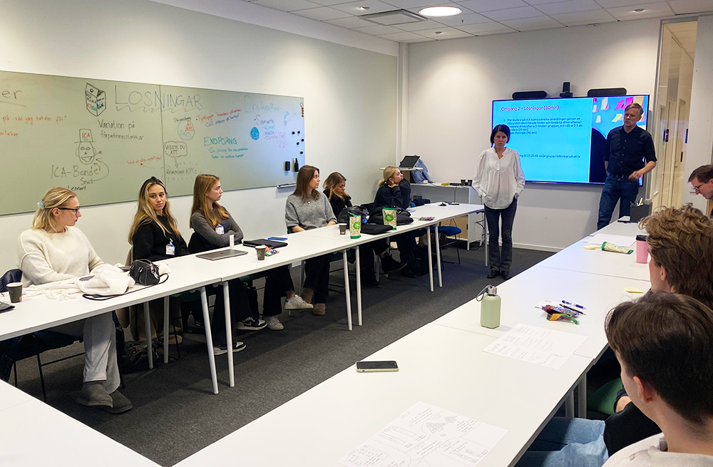 Students sitting around an u-shaped conferance table listening to two reps from ICA running a workshop.