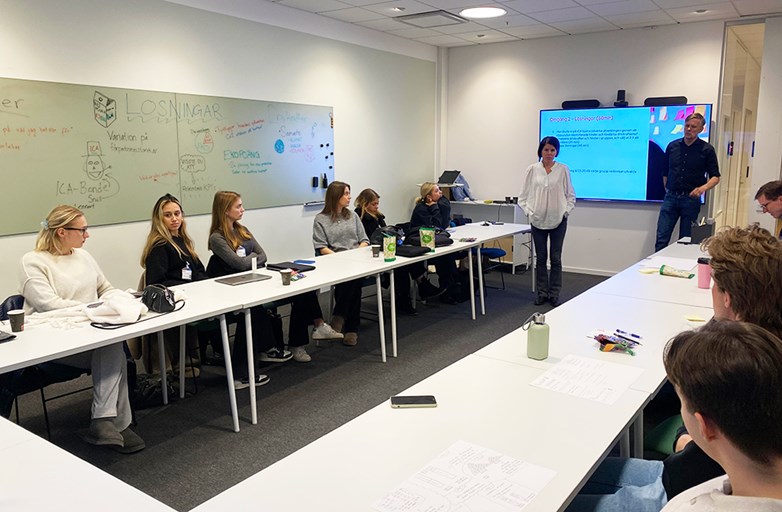 Students sitting around an u-shaped conferance table listening to two reps from ICA running a workshop.