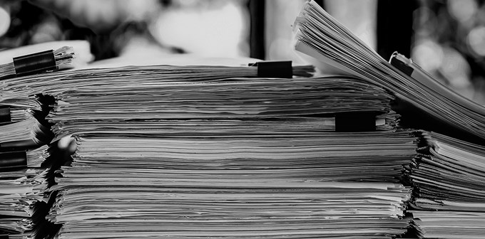 Stack of business report paper file on modern white office desk with bokeh background.