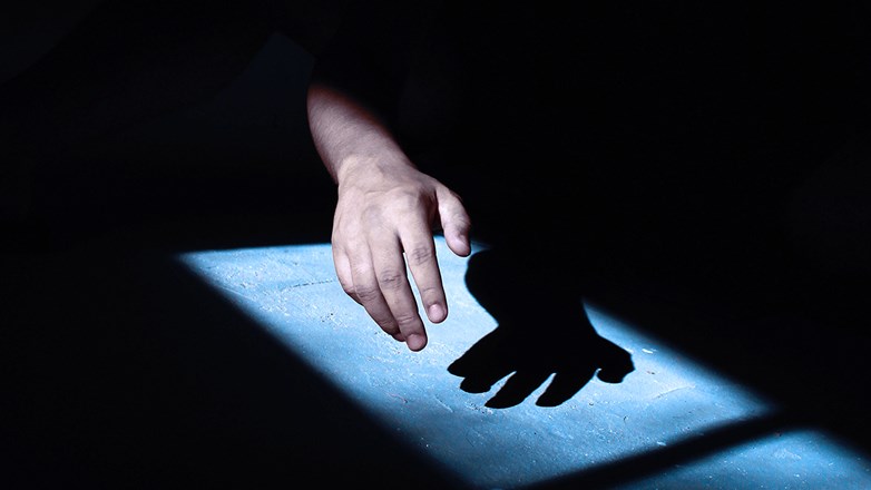 Hand reaching out from the shadow