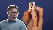 A modified screen shot image of Anders Olofsgård. In the background there's a wooden hand holding a question mark.