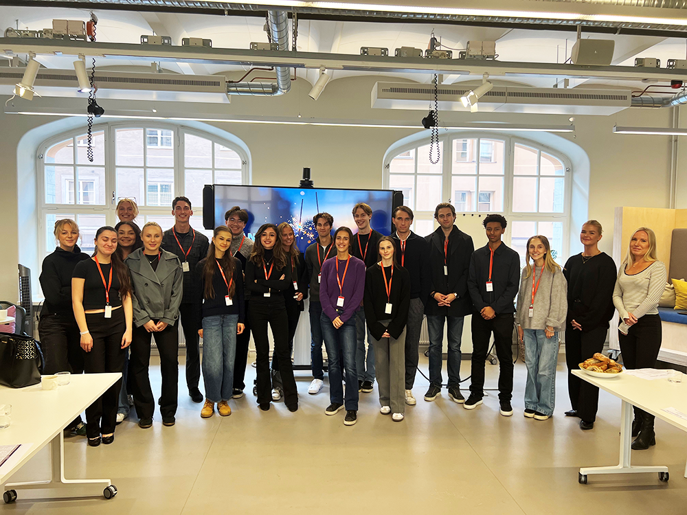 A larger group of students looking into the camera and smiling at Accenture's head office in Stockholm.