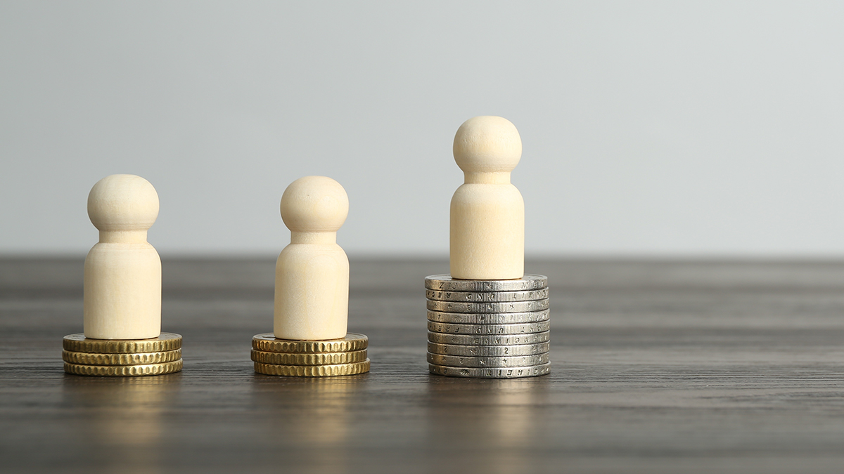 Financial inequality. Human figures and coins on wooden table.