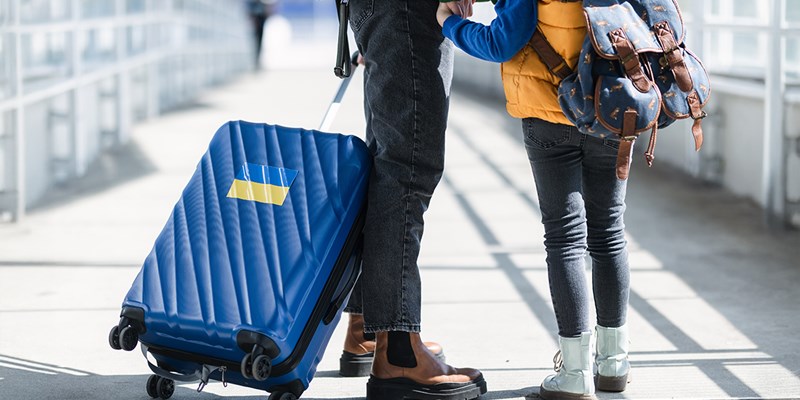 Low section of Ukrainian immigrant family with luggage at train station, Ukrainian war concept.