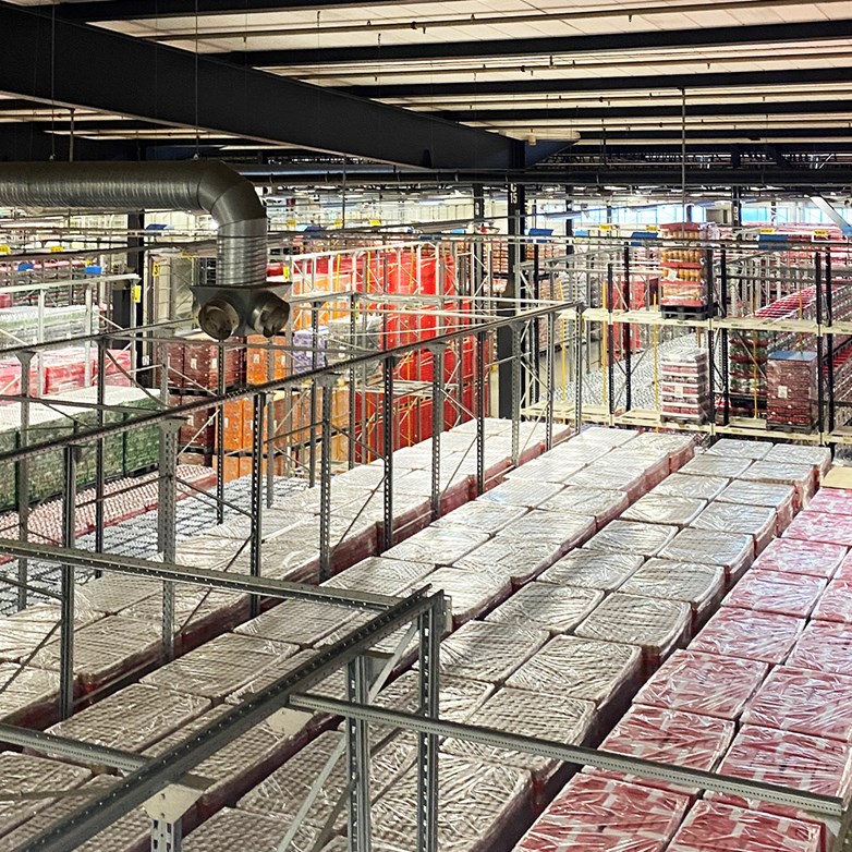 Picture of huge factory floor with beverage stock shelfs and distribution lines at the Coca-Cola factory in Jordbro outside of Stockholm.