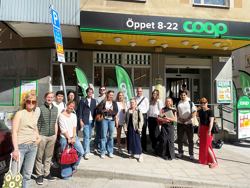 Group of students standing outside a COOP store in a sunny weather.