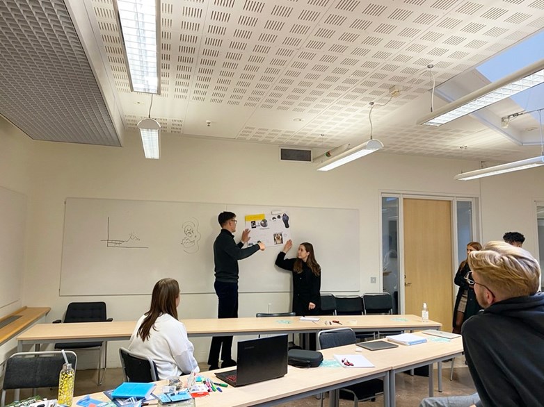 Students presenting in front of a whiteboard at a Clas Ohlson workshop