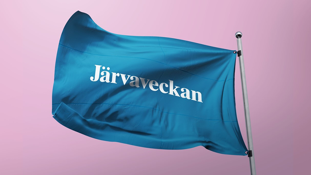Waving light blue flag with "Järvaveckan" printed in white on it. Pink background.