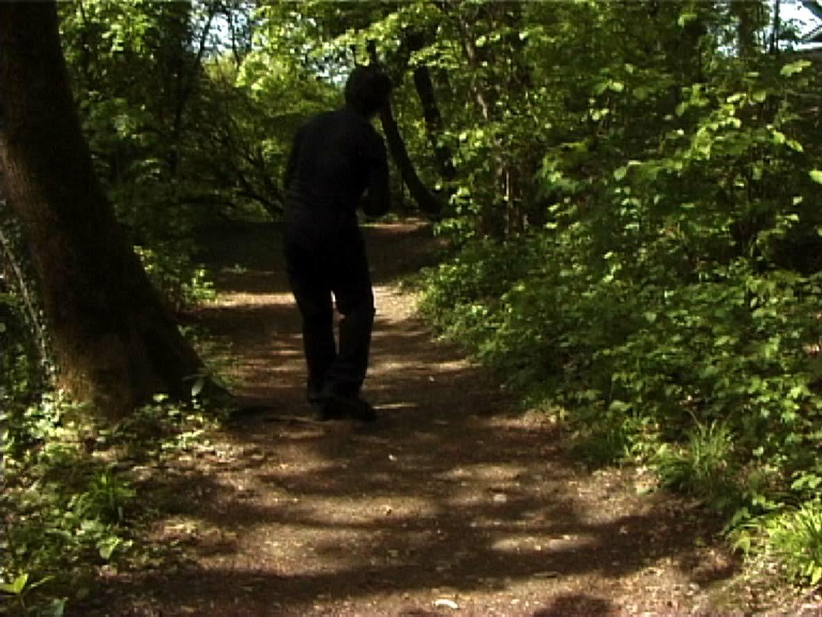 Still from Jumana Emil Abboud's video Al Awda/The Return, showing the artist on a forest path