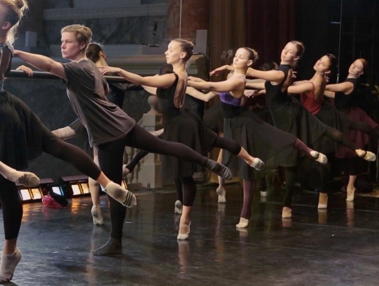The artist in a ballet studio among professional dancers, out of step with the line.