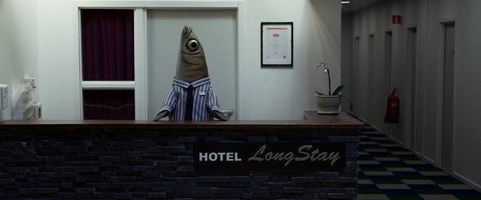 Stop-motion fish characters in the lobby of a drab hotel set, built at doll scale.