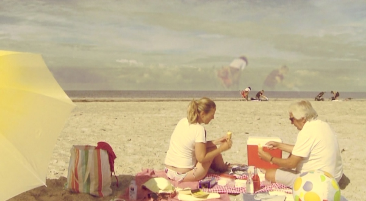  Still from Anneè Olofsson's film Under a Serpent Sun, showing two sunbathers on a beach