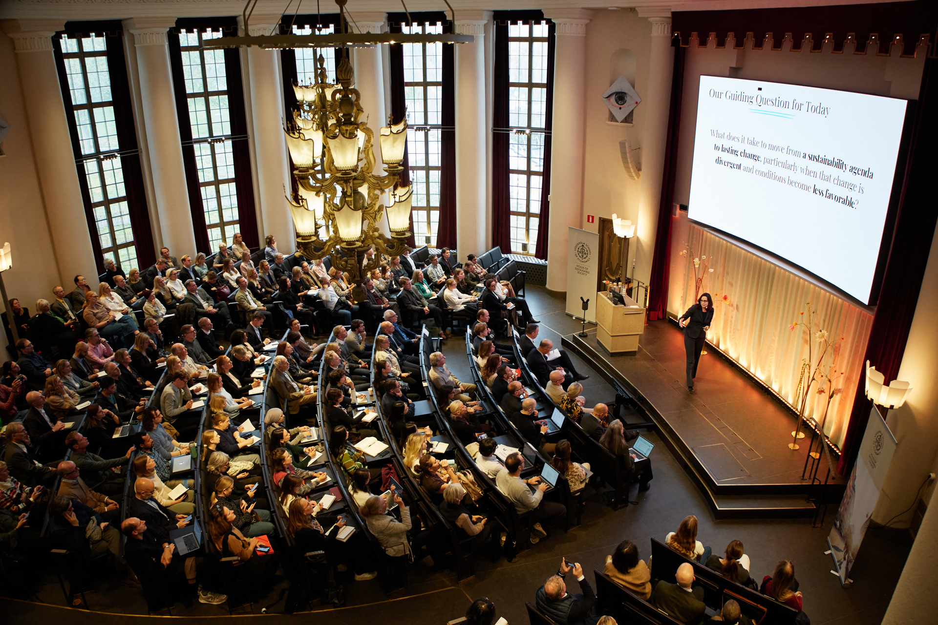 Birds-eye view of a packed Aula at the Stockholm School of Economics as Professor Julie Battilana delivers her keynote during the HoSS Forum 2026.