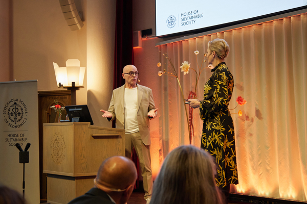 Professor John Hassler stands on stage in the Aula at the Stockholm School of Economics answering questions from the audience at the HoSS Forum 2026.
