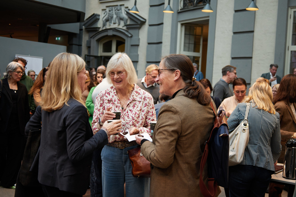 Close-up shot of a group of people deep in discussion in a packed Atrium at the Stockholm School of Economics during the fika break at the HoSS Forum 2026.