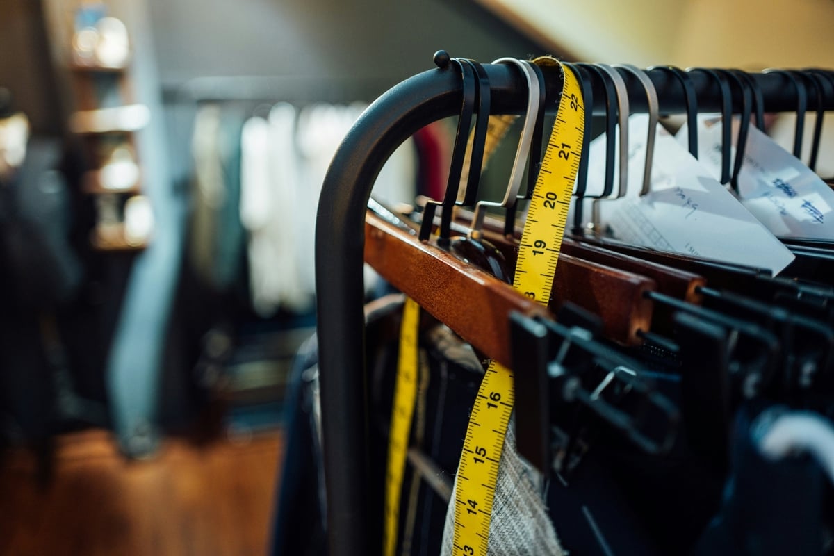 Rack of clothes with a measuring tape hanging on the rack.