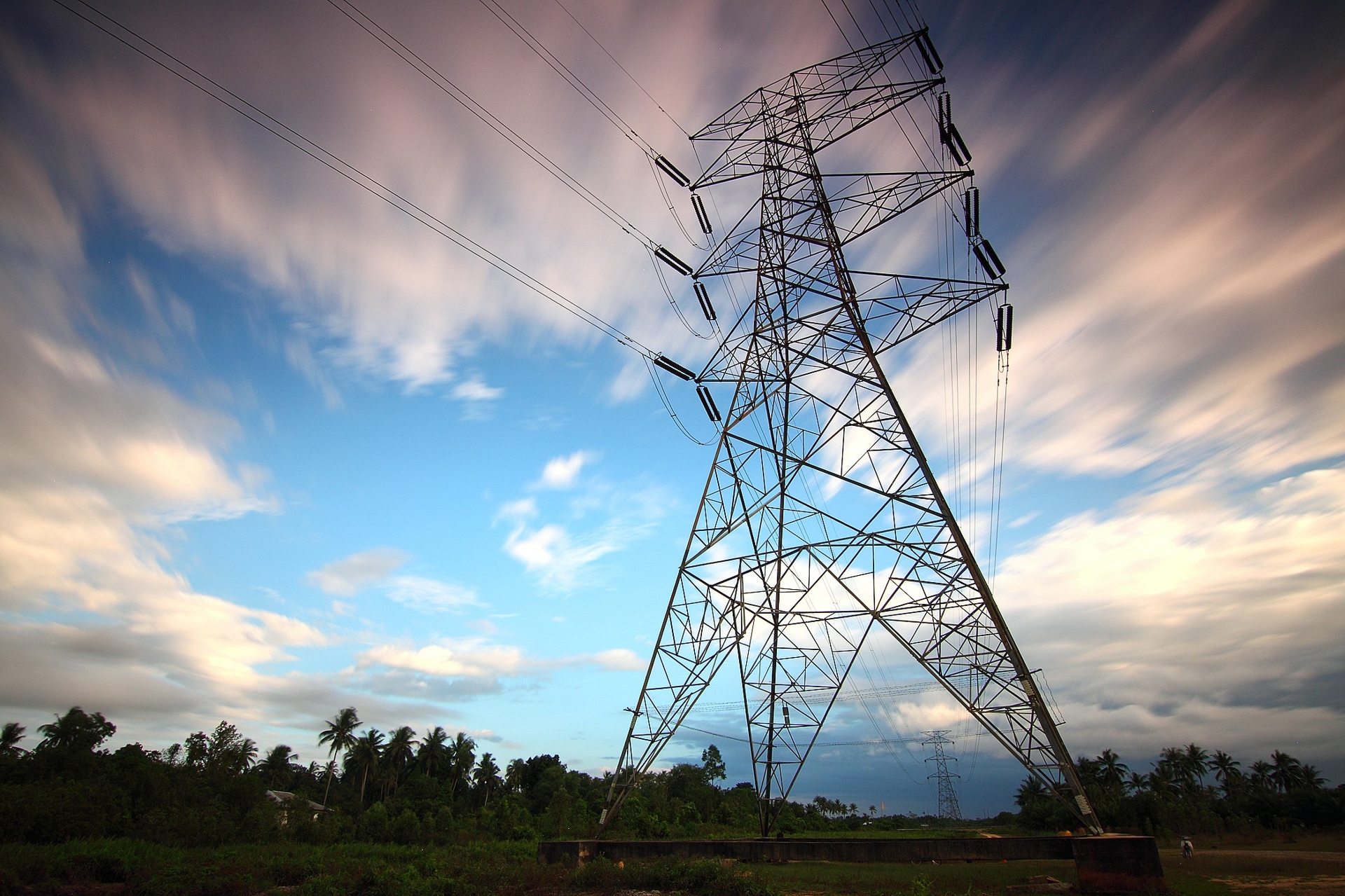 Picture of an electric power transmission tower with trees in the background