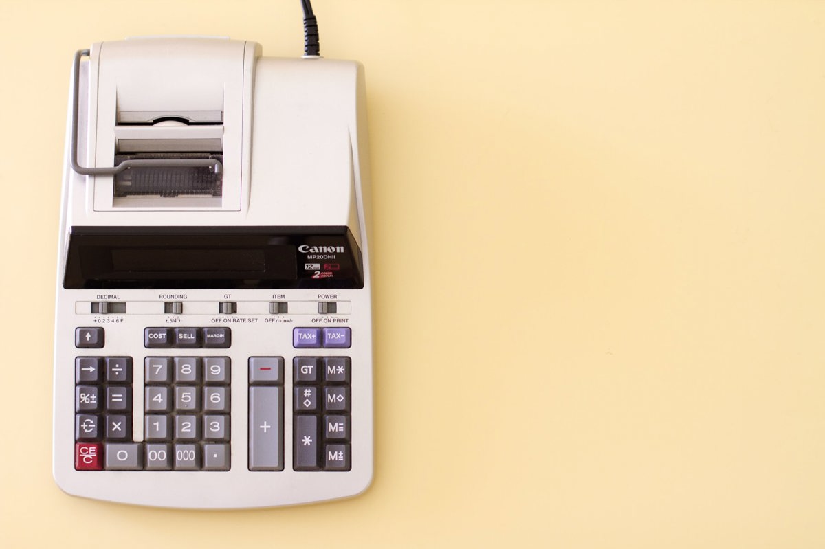 Old-fashioned calculator against a pale yellow background.