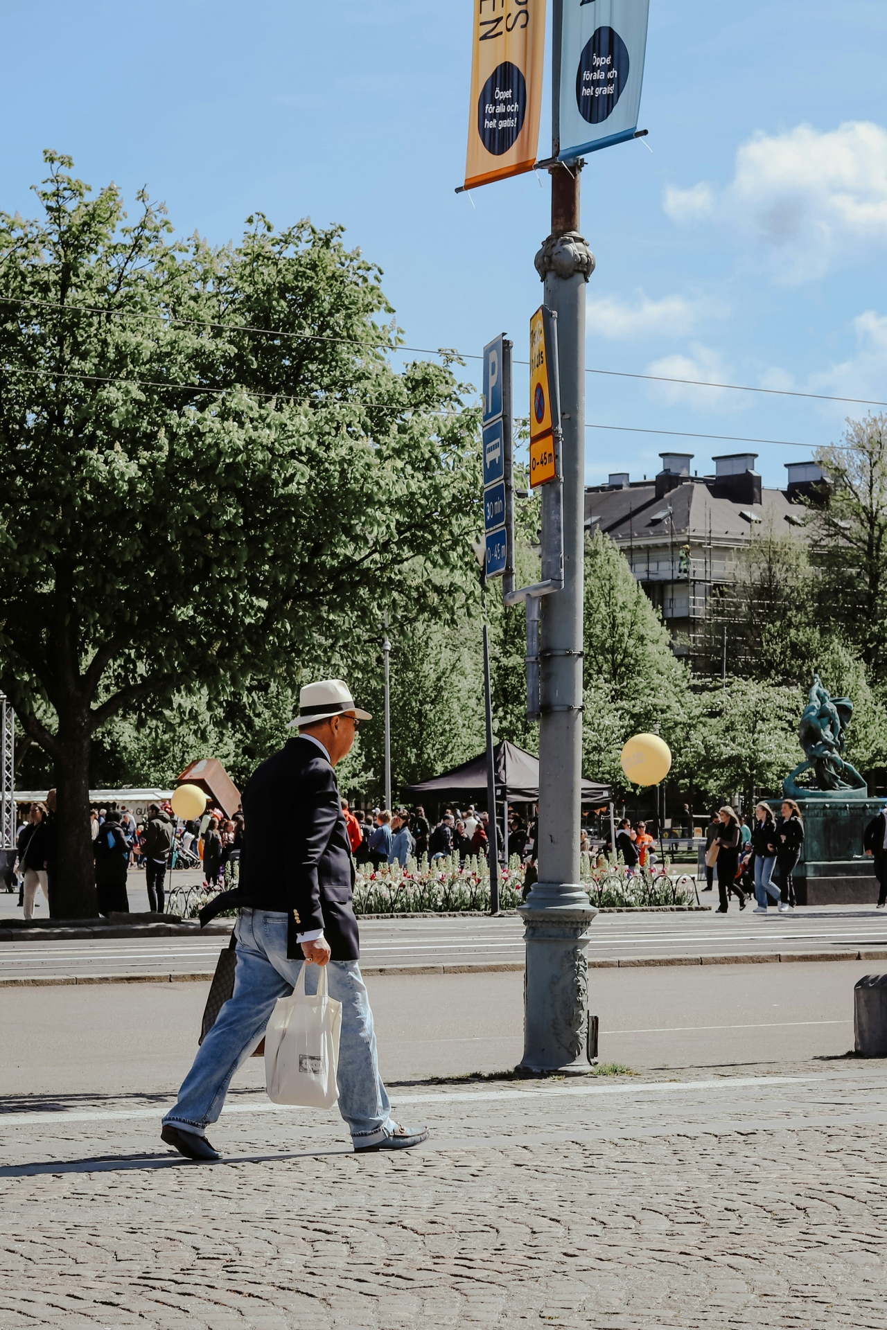 Man walking down the street with a bag in hand on a sunny day.