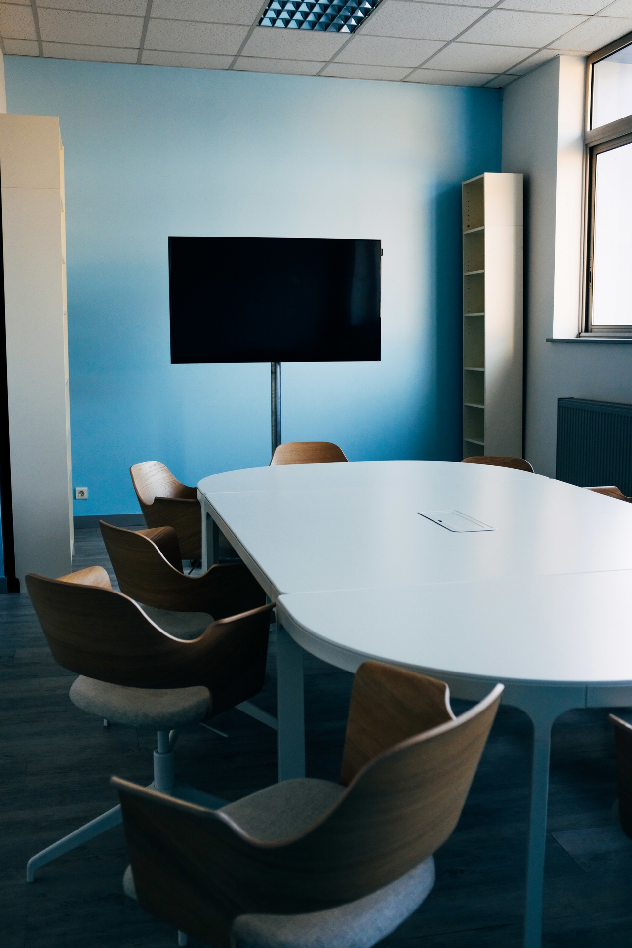 Meeting room with empty chairs facing a black screen on a blue wall.
