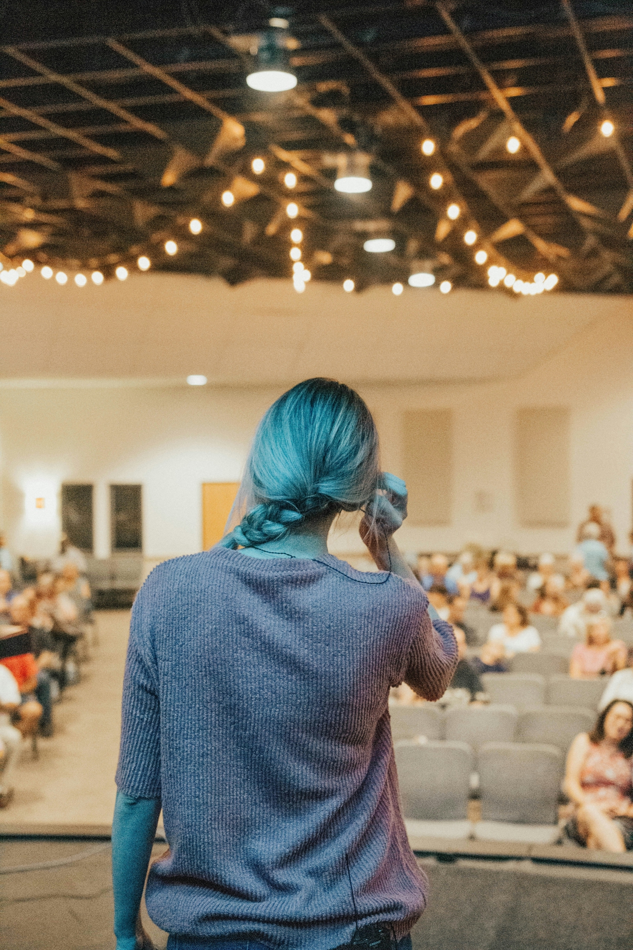 Woman standing in front of an audience, adjusting her earpiece.
