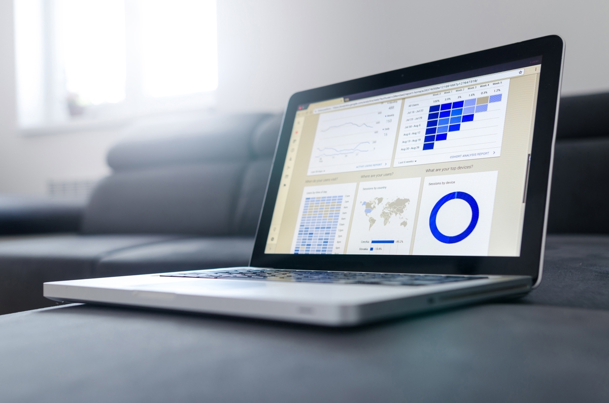 A computer on a grey sofa displaying a dashboard of accounting data.