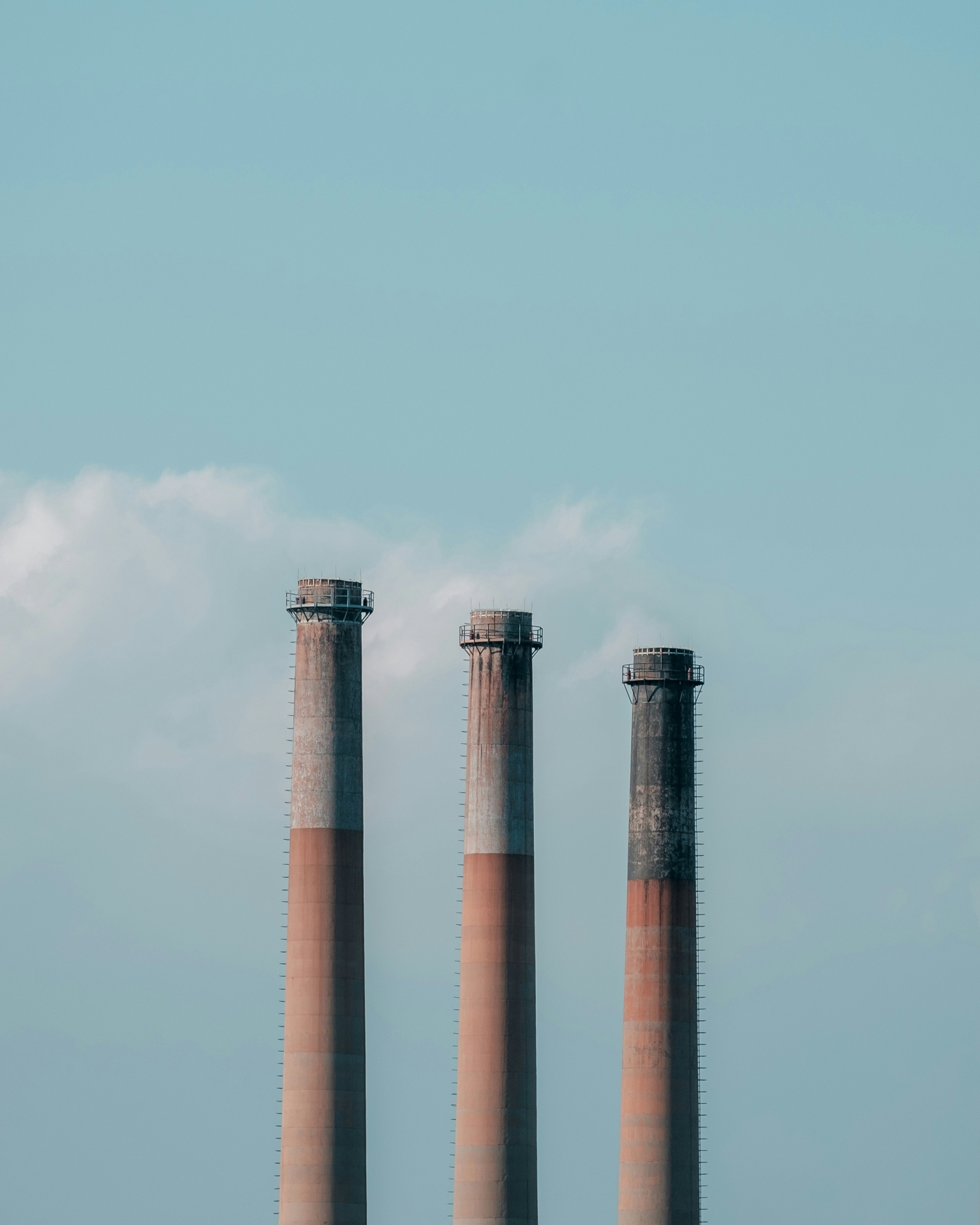 Three industrial exhaust pipes against a blue sky.