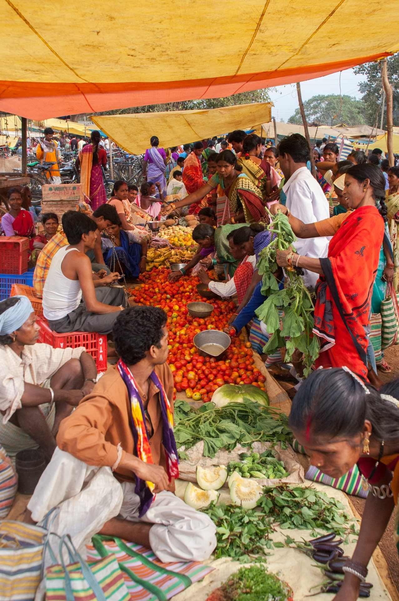 Busy market in India, with owners to the left selling vegetables to the crowds.