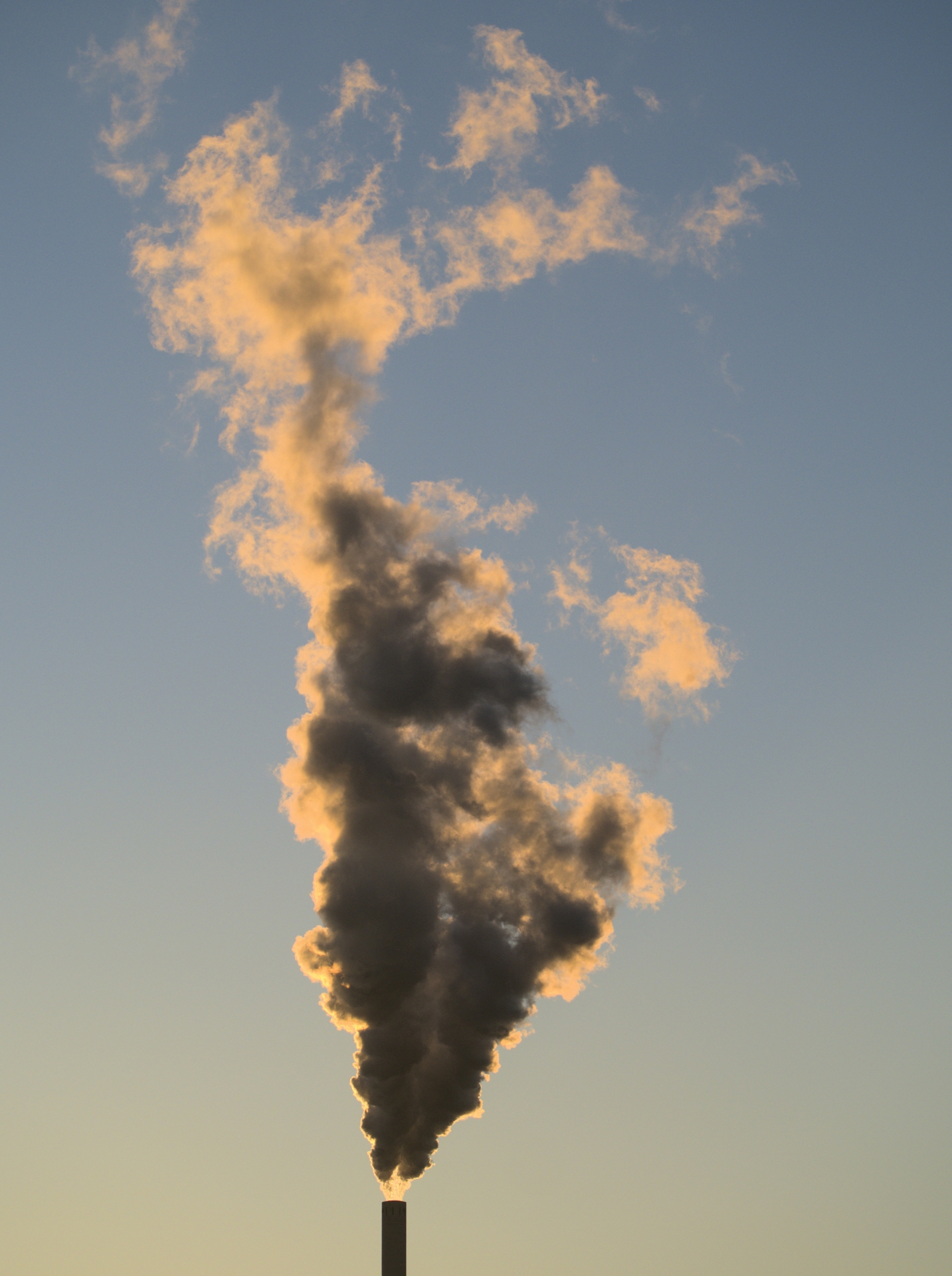 Air pollution emitted from an industrial plant against a blue sky.